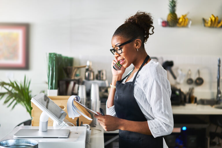 friendly waitress taking order on phone at restaurant and writin