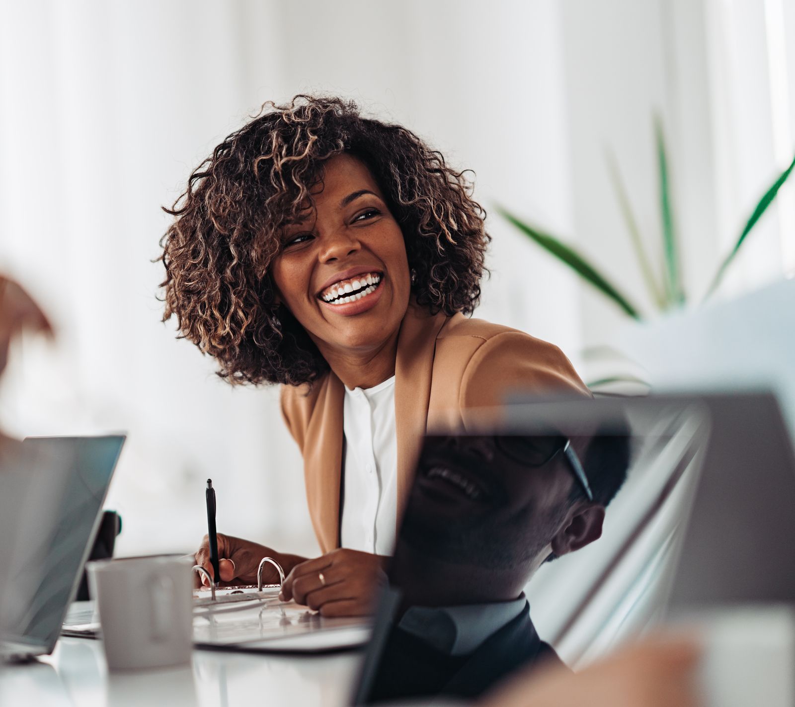 An owner laughing with her team around a meeting table
